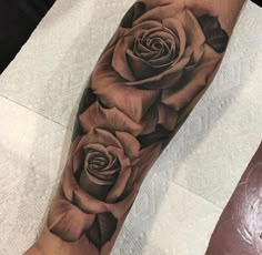 a black and grey rose tattoo on the arm