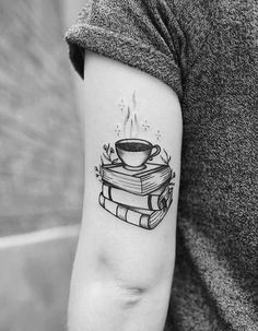 a woman's arm with a cup of coffee on top of books