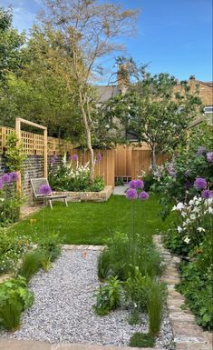 a garden with lots of plants and flowers in the center, along with gravel path