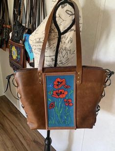 Rustic and refined emerge in this beautiful one of a kind, wearable work of art! Featuring tooled (textured) and painted original artwork by artist Angela Wheat This bag is made of soft flexible genuine leather.  It Can be used as a larger purse, tote, or work bag. Roomy main compartment will fit a laptop up to 13" inside pocket has plenty of space for cellphone and other things. Hand Painted Brown Rectangular Shoulder Bag, Brown Hand Painted Satchel Shoulder Bag, Artistic Hand Painted Leather Shoulder Bag, Artistic Hand Painted Crossbody Shoulder Bag, Western-themed Brown Leather Shoulder Bag, Genuine Leather Purse, Work Bag, Inside Pocket, Leather Purses