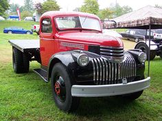 an old red truck is parked in the grass