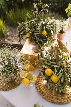 some lemons are sitting in baskets on a table with other citrus fruits and herbs