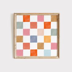 an abstract painting with multicolored squares in a wooden frame hanging on a wall