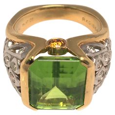 By designer Richard Krementz, known for high quality and exceptional stones. This ring is an attention grabber! It's beautiful green colored Peridot is complemented by a platinum, 18K yellow gold and diamond design/mounting. Emerald cut peridot in partial bezel setting- approximately 11.7mm X 11.0mm 26 round diamonds in various sizes - approximately .74tdw 2 round orange (sapphires) on each side Stamped "750", "PLAT", "RKG" and "1866" Approximate size is 5.5 (can be sized) 7.3dwt Attention Grabber, Yellow Ring, Yellow Rings, Orange Sapphire, Jewelry Fashion Trends, Diamond Design, Bezel Setting, Emerald Cut, Diamond Rings