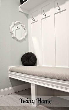 a white bench sitting in front of a wall with hooks on it's sides