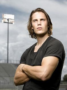 a man standing in front of a stadium with his arms crossed