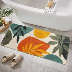 a bath tub sitting next to a rug with flowers on it