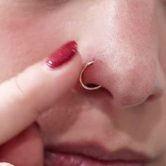 a close up of a person with a nose ring on their nose and one finger touching the nose