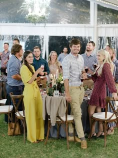 a group of people standing around a table with wine glasses