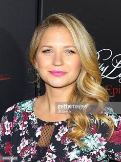 a woman with long blonde hair and pink lipstick posing for the camera at an event