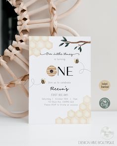 a white card with a bee on it next to a wooden branch and some honeycombs