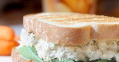 a close up of a sandwich on a plate with carrots in the back ground