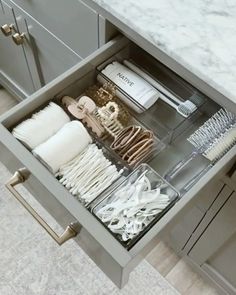 an open drawer in a kitchen filled with white dishes and utensils on top of marble counter tops