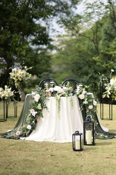 a table with white flowers and greenery is set up for an outdoor wedding ceremony