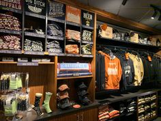 a store filled with lots of clothing and hats on display in front of wooden shelves