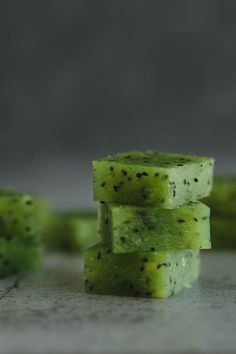 three pieces of green food sitting on top of a counter next to each other with tiny black dots all over them