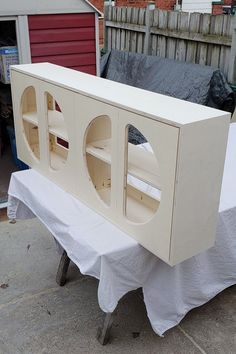 a table with a white plastic cover on it and some shelves in the back ground