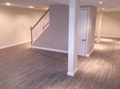 an empty living room with stairs leading to the second floor and another door on the other side