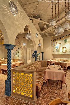 the inside of a restaurant with many tables and chairs, lights hanging from the ceiling