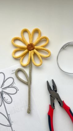 a crochet flower next to some scissors and thread on a piece of paper