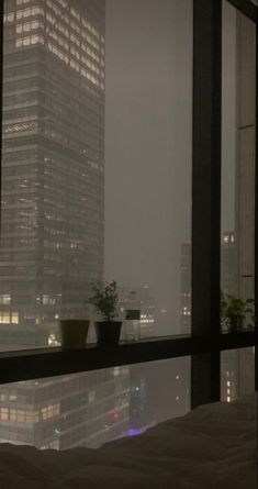 a bed sitting in front of a window next to a tall building with lots of windows