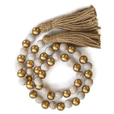 two strands of white and gold beads with brown tassels on each bead