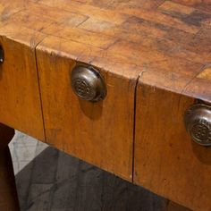 an old wooden table with two metal knobs on the top and one drawer open