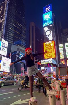 a woman standing on top of a pole in the middle of a city