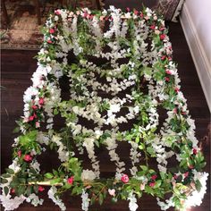 white flowers and greenery are arranged on the floor in a room with wooden floors