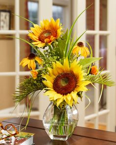 a vase filled with sunflowers sitting on top of a table next to a book