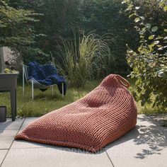 an orange knitted bean bag sitting on the ground next to a chair and table