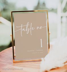 the table numbers are placed on top of a wooden stand with feathers in front of it