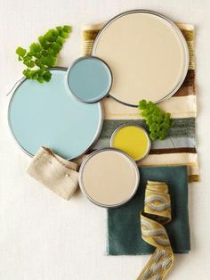 four different colors of paint sitting next to each other on top of a cloth covered table