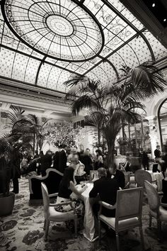 black and white photo of people sitting at tables in a restaurant with glass ceilinging