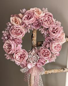 a wreath with pink flowers hanging on a tree branch