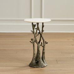 a white table topped with trees on top of a hard wood floor next to a wall