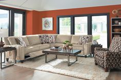 a living room with orange walls and furniture in the center, including a sectional couch