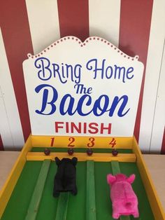 two stuffed animals sitting in front of a sign that says bring home the bacon finish