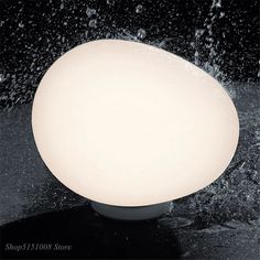 a white ball sitting on top of a black table next to water splashing around it