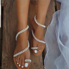 a bride's wedding shoes and veil on a wooden floor with her feet in the sand