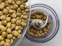 a food processor filled with chickpeas on top of a white table next to a spoon