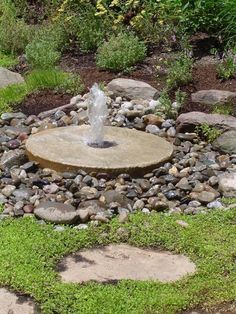 a water fountain surrounded by rocks and grass