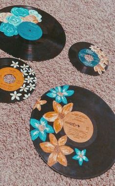 three records with flowers painted on them sitting on the floor in front of a carpet