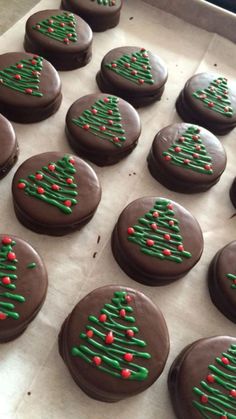 chocolate cookies decorated with green and red icing in the shape of christmas trees on a baking sheet