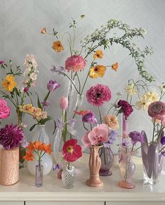 there are many different vases with flowers in them on the table next to each other