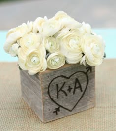 a wooden box filled with white flowers on top of a table