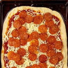 a pepperoni and cheese pizza on a baking sheet in a pan, ready to go into the oven