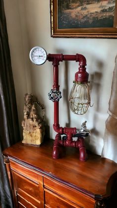 an old fashioned lamp on top of a wooden dresser next to a painting and clock