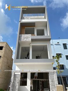 a man standing on the side of a tall white building with windows and balconies