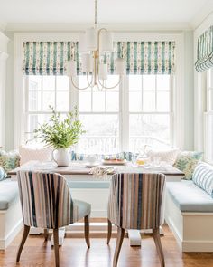 a dining room table with two chairs and a bench in front of the window,